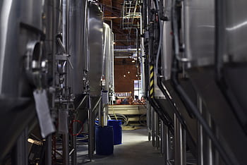 Inside view of a modern brewery with large stainless steel tanks and machinery for beer production. HD wallpaper