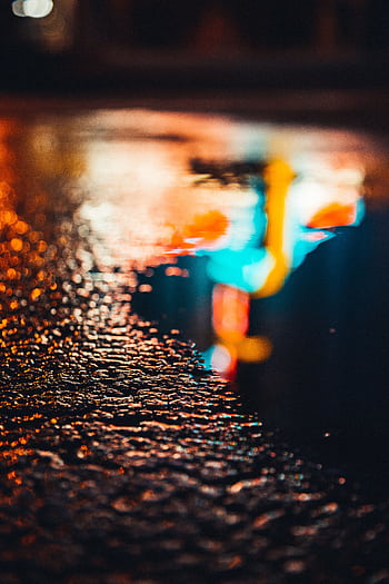 Vibrant neon lights reflect on a wet street creating a colorful abstract scene at night. HD phone wallpaper