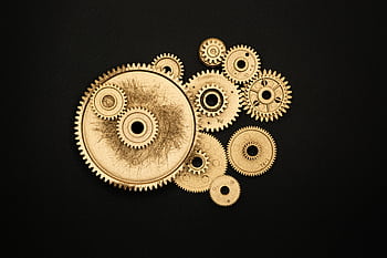 Close-up of golden cogs and gears arranged on a black background showcasing industrial precision. HD wallpaper