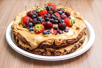 Delicious layered chocolate cake with fresh berries and peanut butter cream on a plate. HD wallpaper