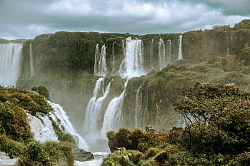 Breathtaking view of Iguazu Falls in Brazil, surrounded by vibrant rainforest and mist. HD wallpaper