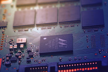 Detailed of an electronic circuit board showing microchips and intricate wiring in a modern technological setting. HD wallpaper
