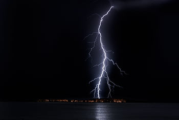 Stunning nighttime lightning bolt captured over ocean, casting eerie glow in Uruguay. HD wallpaper