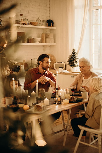 Family enjoying a warm holiday dinner together with candles and laughter. HD phone wallpaper