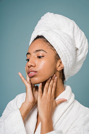Young woman in a spa setting applying skincare with a fresh clean look. HD phone wallpaper
