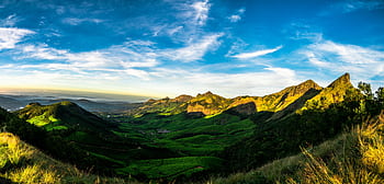 Vibrant landscape of a green valley and majestic mountains under a bright blue sky. HD wallpaper