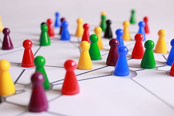 A strategic arrangement of colorful pawns connected on a game board, symbolizing networking and teamwork. HD wallpaper