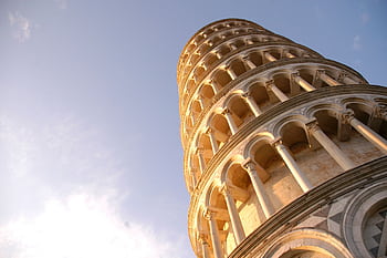 Low angle view of the Leaning Tower of Pisa, a famous Italian landmark under a clear sky. HD wallpaper