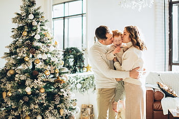 A joyful family embraces near a beautifully decorated Christmas tree during the festive season. HD wallpaper