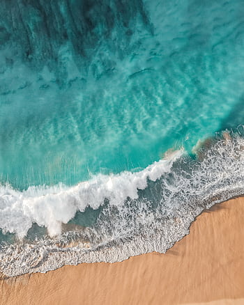 Stunning aerial of turquoise waves crashing onto a sandy beach, capturing natural beauty and surf essence. HD phone wallpaper