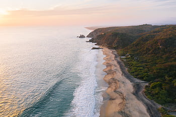 A breathtaking aerial view of the Oaxaca coastline, showcasing the ocean and cliffs at sunset. HD wallpaper
