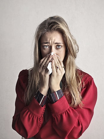Portrait of a woman sneezing with a tissue, depicting flu symptoms. HD phone wallpaper