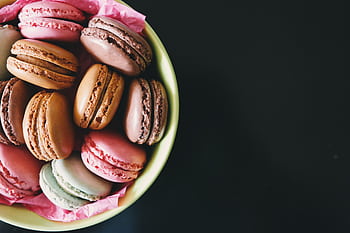 A bowl of assorted colorful macarons on a dark table. Perfect for dessert inspiration. HD wallpaper