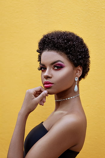 Stylish portrait of a woman with afro hair, bold makeup, and elegant jewelry against a yellow backdrop. HD phone wallpaper