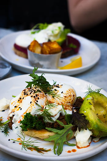 Delicious poached eggs served with avocado and fresh greens, perfect for a healthy gourmet brunch. HD phone wallpaper