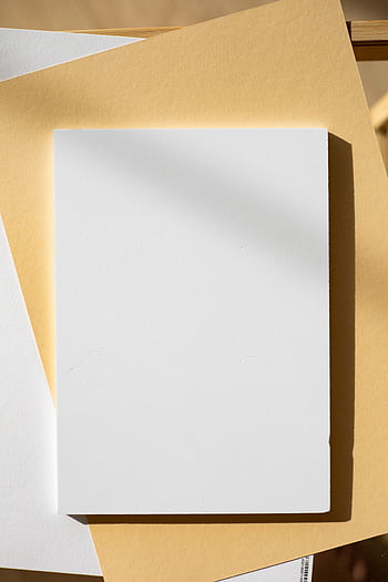 A high-angle shot of blank paper on colored surfaces, offering warm shadows and minimalist design. HD phone wallpaper