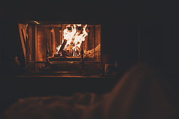 A cozy indoor fireplace with vivid flames, offering a warm and relaxing winter ambiance. HD wallpaper
