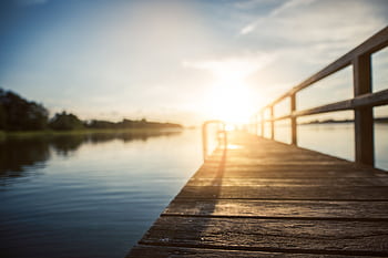 Peaceful sunset over a calm lake, captured from a wooden boardwalk in Kiel, Germany. HD wallpaper