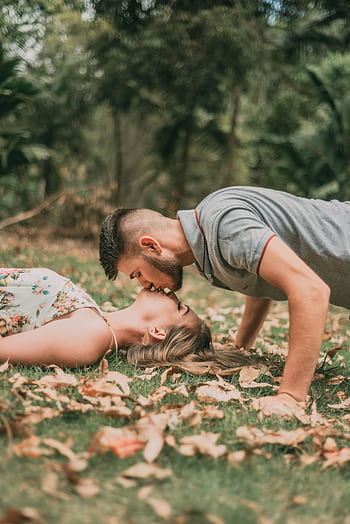 Young couple kissing on grass surrounded by fallen autumn leaves. HD phone wallpaper