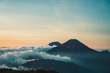 Beautiful sunrise view of Mount Sindoro with clouds and serene landscape in Java, Indonesia. HD wallpaper
