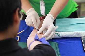 A healthcare professional administering an injection to a patient's arm during a medical procedure. HD wallpaper