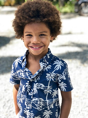 Adorable young boy with an afro smiling brightly outdoors on a sunny day. HD phone wallpaper