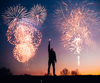 A person celebrates under vibrant fireworks in the evening sky in Kragujevac, Serbia. HD wallpaper