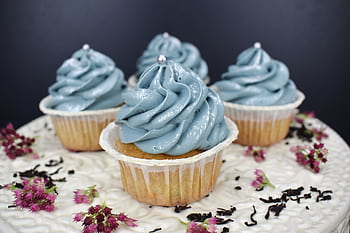 Close-up of blue frosted cupcakes with floral decoration. Perfect for parties and celebrations. HD wallpaper