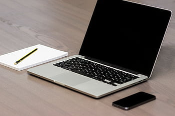 A clean and simple office desk setup featuring a laptop, smart, and notebook with pencil. HD wallpaper