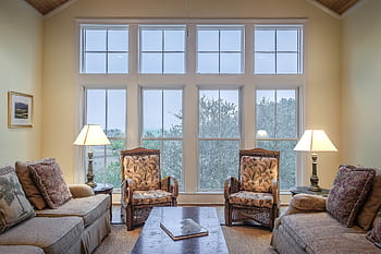A cozy living room showcasing elegant furniture with large glass windows and warm lighting. HD wallpaper