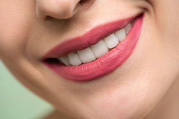 Vivid close-up of a woman's smile showcasing red lipstick and white teeth on a light background. HD wallpaper