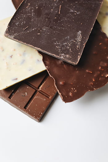 A stack of delectable dark, milk, and white chocolate bars on a white surface. HD phone wallpaper