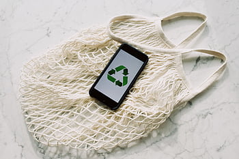 An eco-friendly message displayed on a smart resting on a reusable mesh bag, symbolizing sustainability. HD wallpaper