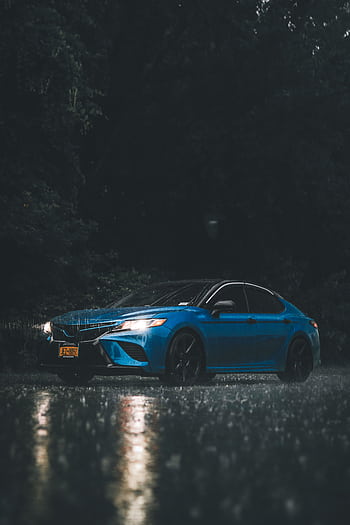 A striking of a blue car parked in the rain on a dark night. HD phone wallpaper