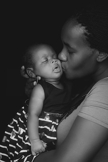 A touching black-and-white of a mother kissing her baby, symbolizing love and affection. HD phone wallpaper