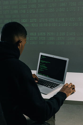 A programmer engaged in coding on a laptop in a tech-focused workspace with a digital interface. HD phone wallpaper
