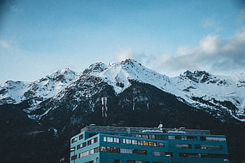 Stunning view of snow-capped mountains overlooking a modern building in Innsbruck, Austria. HD wallpaper