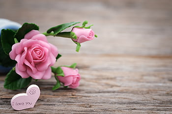 Pink roses and a heart-shaped note on wooden background, perfect for romantic events. HD wallpaper