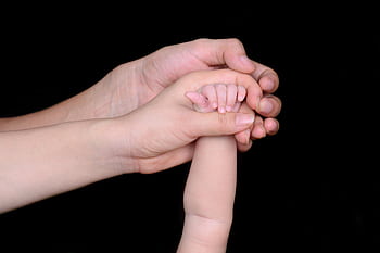 A close-up featuring a baby's hand being held by a parent's hand, symbolizing love and protection. HD wallpaper