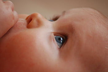 A heartwarming close-up of a baby's face showcasing innocent eyes with a soft, gentle expression. HD wallpaper