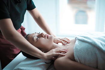 A serene spa massage session with a woman relaxing on a table, receiving a calming neck massage. HD wallpaper