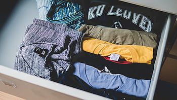 A neat arrangement of clothes and T-shirts in a drawer, showcasing casual wear. HD wallpaper