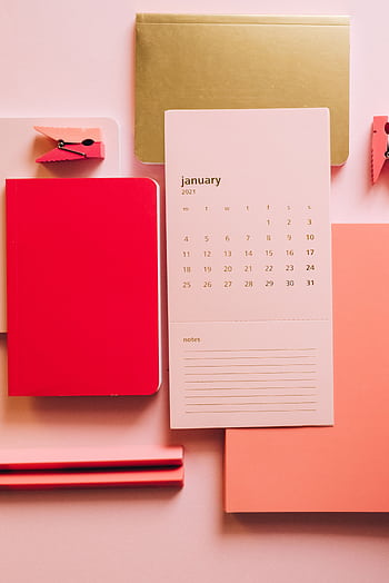 A flatlay of a January calendar surrounded by colorful notebooks and stationery. HD phone wallpaper