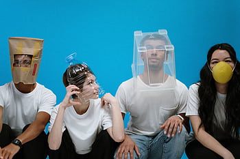 Four people wearing humorous DIY face masks against a blue background, showcasing creativity and humor. HD wallpaper
