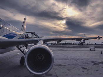 A passenger airplane is parked on the tarmac at sunset, with another aircraft in the background. HD wallpaper