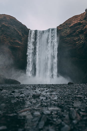 Stunning view of Skógafoss waterfall cascading in a dramatic, misty Icelandic landscape. HD phone wallpaper