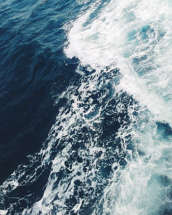 A dramatic aerial shot of ocean waves crashing, showcasing the vibrant blue sea off Cambodia's coast. HD phone wallpaper