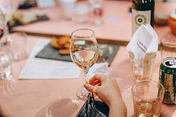 A hand holding a wine glass at an elegant dining setting, perfect for celebrations. HD wallpaper