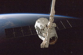 A satellite orbiting Earth with a view of the planet from space. HD wallpaper