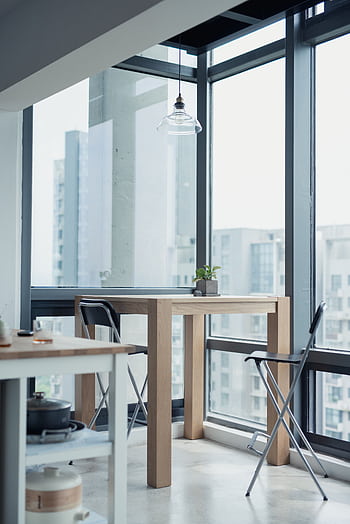 Bright modern apartment interior featuring minimalist wooden furniture and a glass window with a cityscape view. HD phone wallpaper